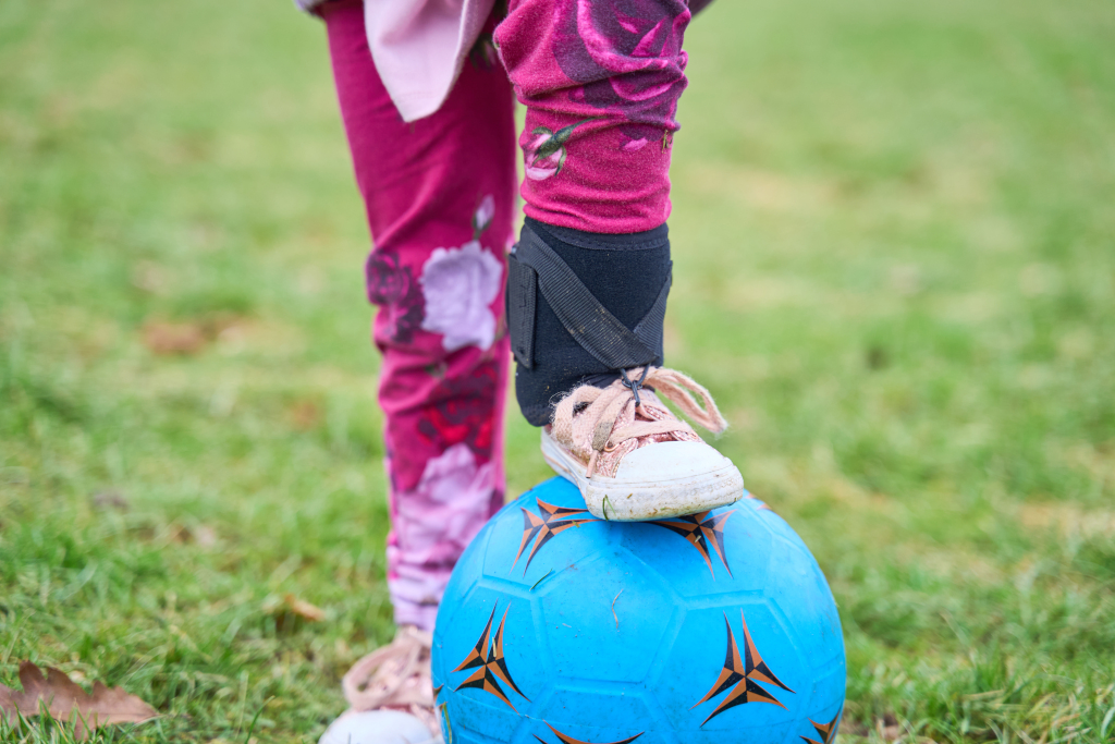 Child climbing up a climbing frame and smiling, with a caregiver assisting